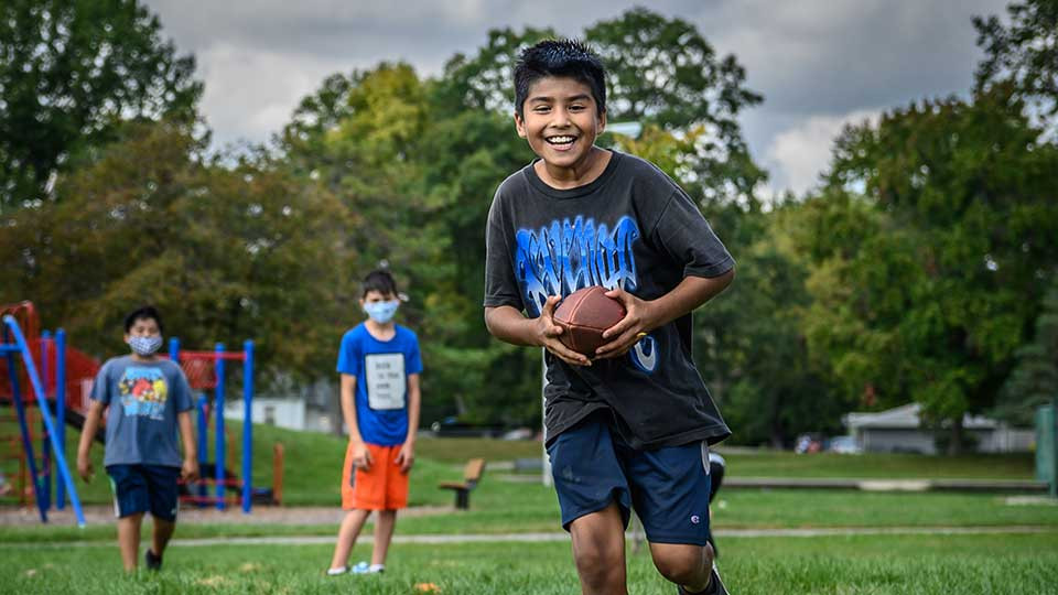 Child smiling while running with football