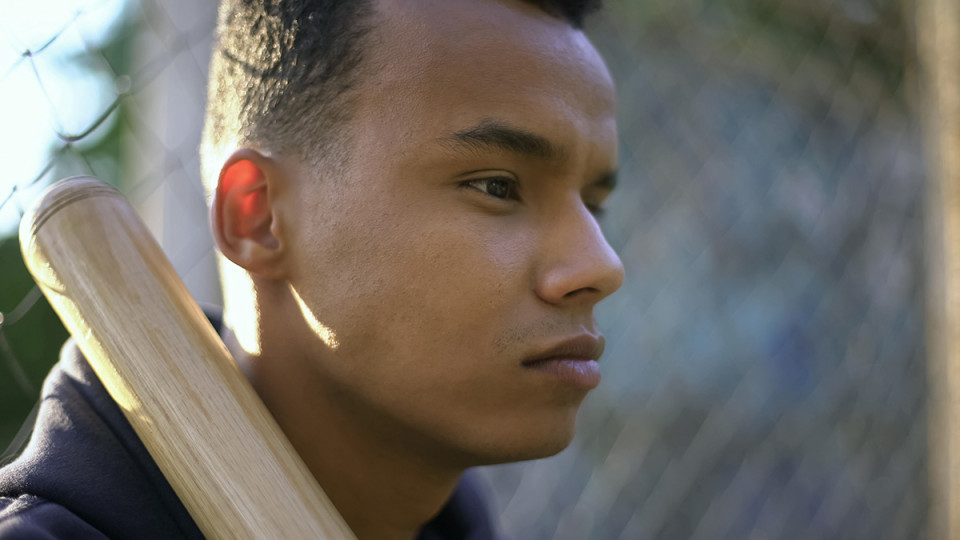 young man thinking with a baseball bat on his shoulder