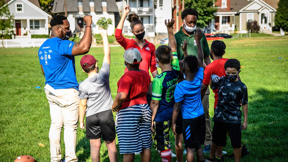 Group of campers outside with their hands in the air