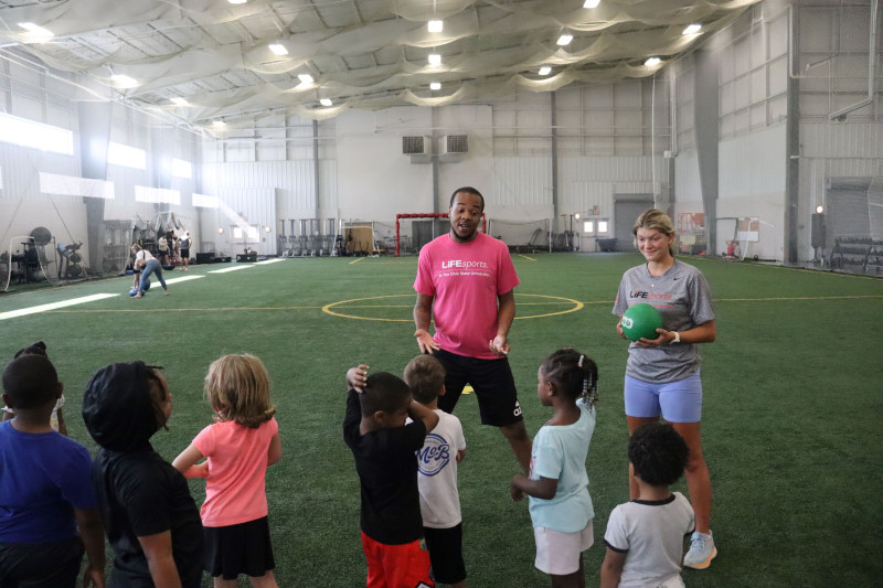 students teach children in indoor arena